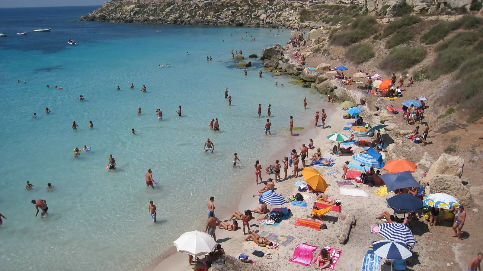 Cala Azzurra in Favignana with shallow turquoise water and families on the beach
