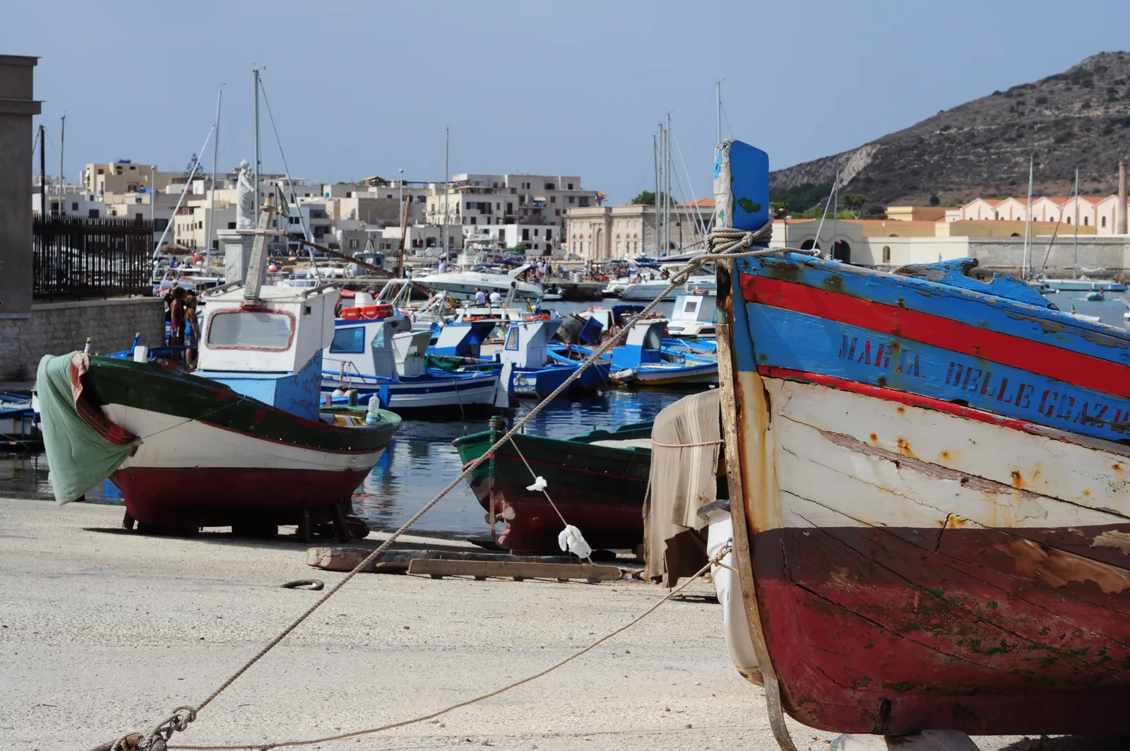 Barche colorate nel porto di Favignana con il paese e il monte Santa Caterina sullo sfondo