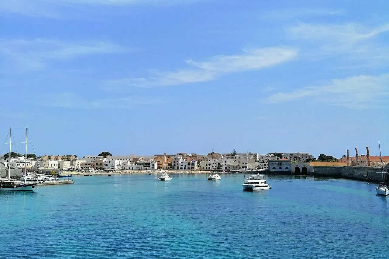 Il porto di Favignana con il paese e le barche ormeggiate nel mare turchese