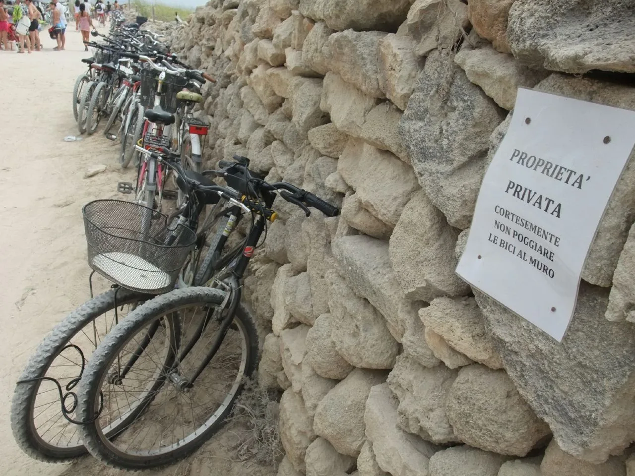 Biciclette parcheggiate lungo un muro di tufo vicino a una spiaggia di Favignana